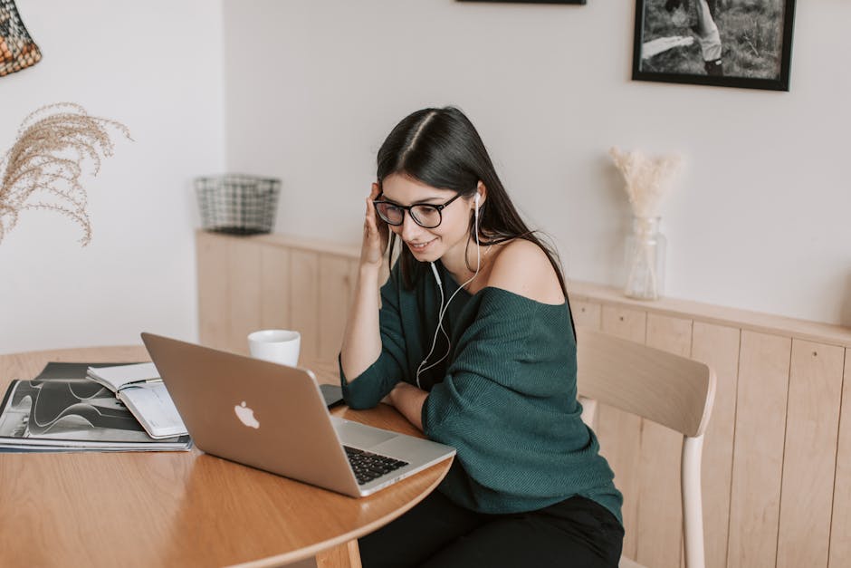 Smiling woman using laptop and earbuds for online learning in a cozy home setting.