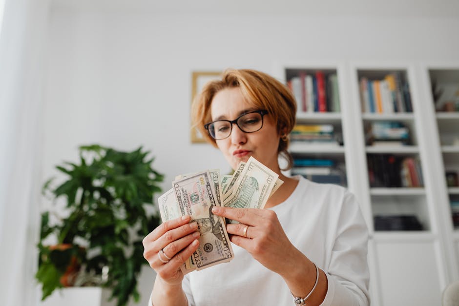 Woman with eyeglasses counting dollar bills in a home setting