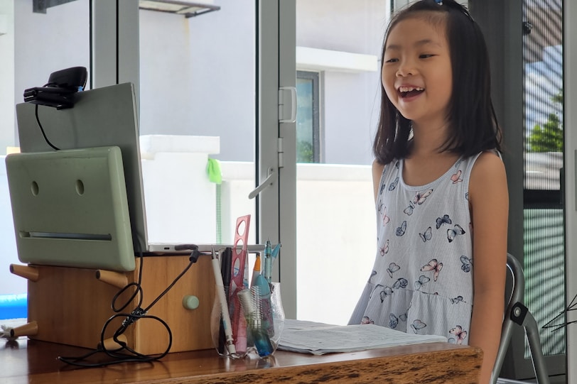 a little girl standing in front of a computer