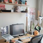 Contemporary home office setup with desk, computer, and creative shelves displaying figurines and art.