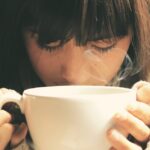 Woman savoring the aroma of a hot coffee cup in a cozy setting.