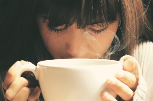 Woman savoring the aroma of a hot coffee cup in a cozy setting.